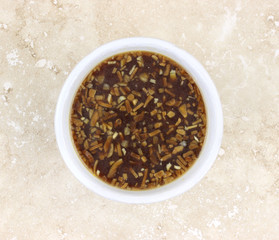 Onion soup in a white bowl atop marble