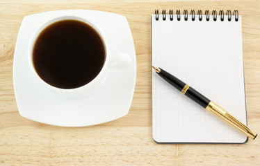 Blank pad of paper with pen and coffee on wooden background