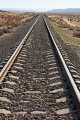 Straight railway in the desert converging to the horizon