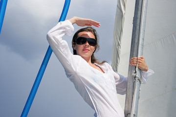 The girl stand on a yacht nose keeping for a sail during a storm