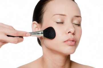 Young and attractive woman applying blusher