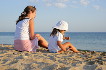 Mother and the daughter sit on a beach about the sea