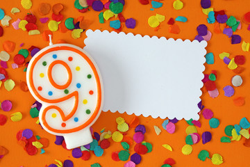 Number nine birthday candle on orange background