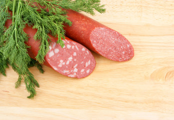 Sausage and greens on wooden background