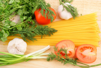 Spaghetti and fresh vegetables on wooden background