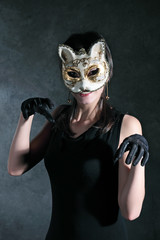 Girl in the Venetian mask of a cat against a dark background