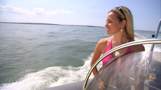Beautiful blonde girl having fun in speedboat in summer