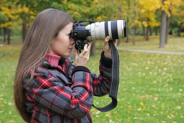 The girl with the camera photographs an autumn landscape