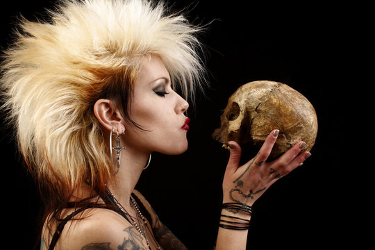 A sexy punk rocker woman holding a human skull.