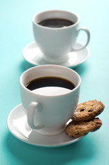Two coffee cups with cookies on blue background
