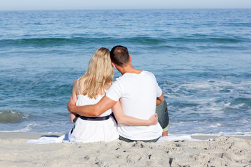 Fototapeta premium Affectionate couple sitting on the sand at the beach