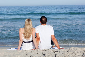 Enamoured couple sitting on the sand at the beach