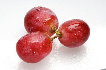 three wet red grapes isolated on white background