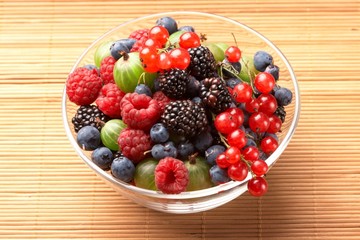 Fruit mix in the glass container, on a table from straw
