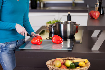 junge frau schneidet paprika in der küche