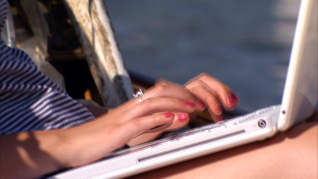 Beautiful blonde girl with her laptop aboard a luxury yacht
