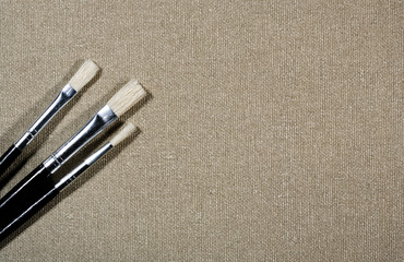 Different paintbrushes over canvas background