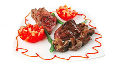 fillet mignon on a white plate and tomatoes