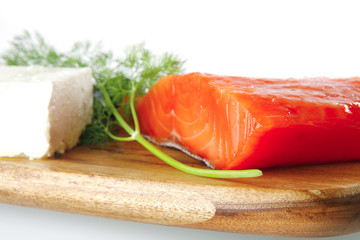 pink smoked salmon on wooden plate with white cheese