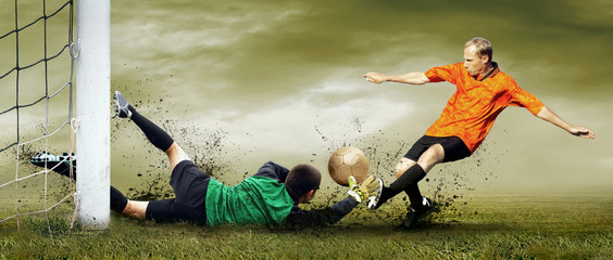 Shoot of football player and goalkeeper on the outdoors field