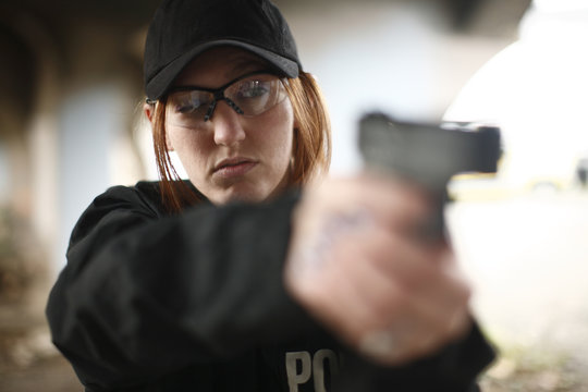 Female police officer aiming pistol.
