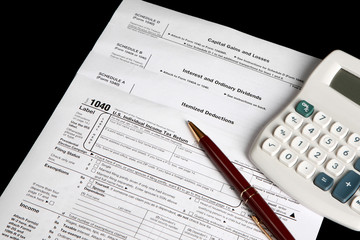 Tax forms on a black background with calculator and pen