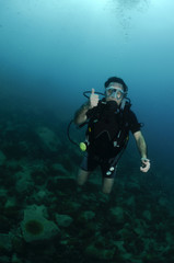 Fototapeta na wymiar young male scuba diver swimming over coral