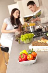 Young couple in kitchen choosing recipe from cookbook
