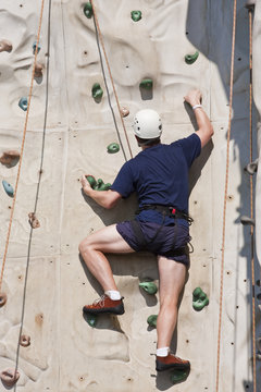 Man Climbing Rock Wall with Ropes