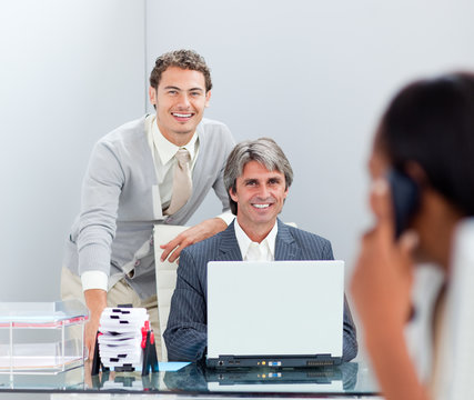 Smiling businessmen working at a computer together