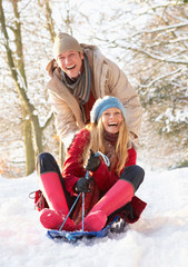 Couple Sledging Through Snowy Woodland