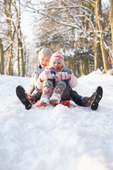 Obraz premium Boy And Girl Sledging Through Snowy Woodland