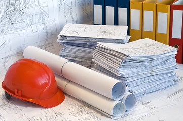 Orange helmet and heap of project drawings