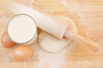 Pastry, flour, milk and eggs on wooden background