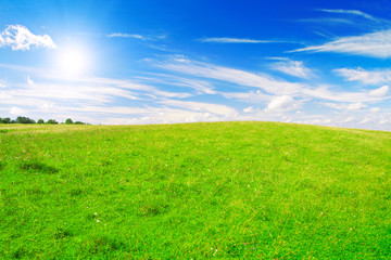 Obraz na płótnie Canvas Green hill under blue cloudy sky whit sun