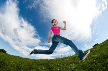 Fototapeta na wymiar Girl running, jumping against blue sky