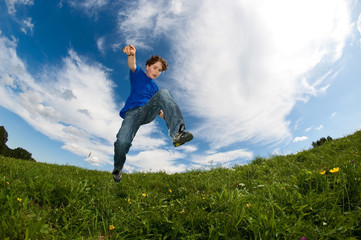 Boy jumping, running against blue sky