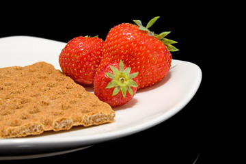 white plate with trawberry and cracker