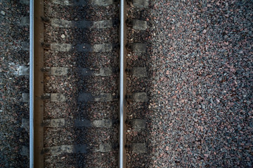 Rails and cross ties of railway among stones at left