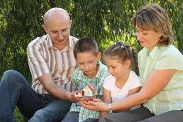 family in fall park. family is sitting looking at wendy house.