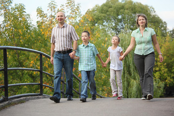 family is walking on bridge in early fall park
