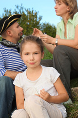 family in park. woman drawing whiskers and beard on man's face
