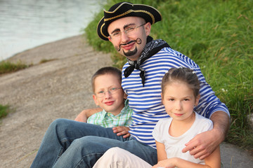 man in pirate suit with son and daughter near pond in fall park