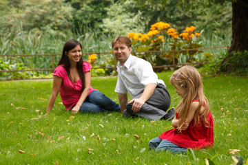 Fototapeta premium Parents together with little girl have rest in summer garden