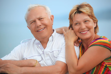 Smiling elderly married couple on veranda near seacoast