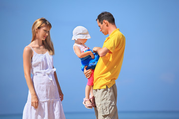Happy family with little girl in white hat against sea