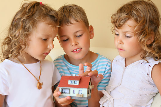 children three together keeping in hands model of house