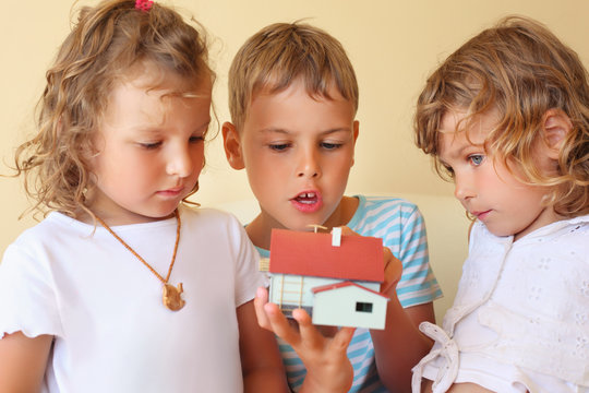 children three together keeping in hands model of house