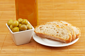Bread, olive oil bottle and olives