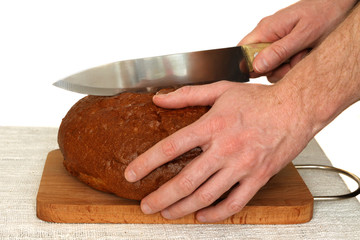 Man slicing grain bread on a wooden board